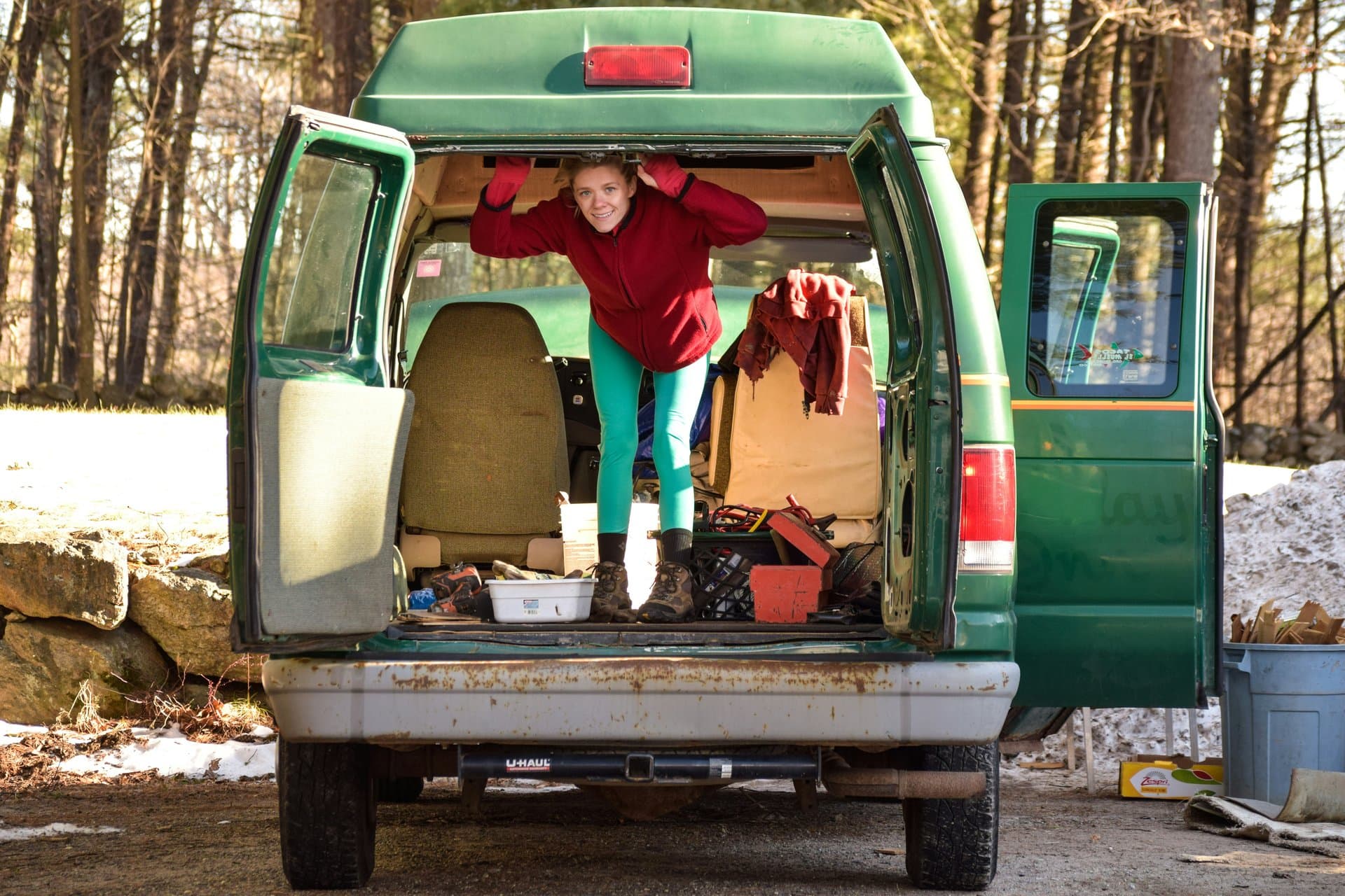 Personne installée à l'arrière d'un van vert en forêt